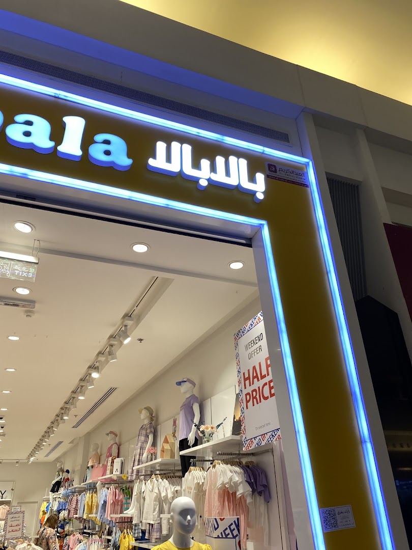 The entrance of a brightly lit clothing store with mannequins displaying children's fashion.