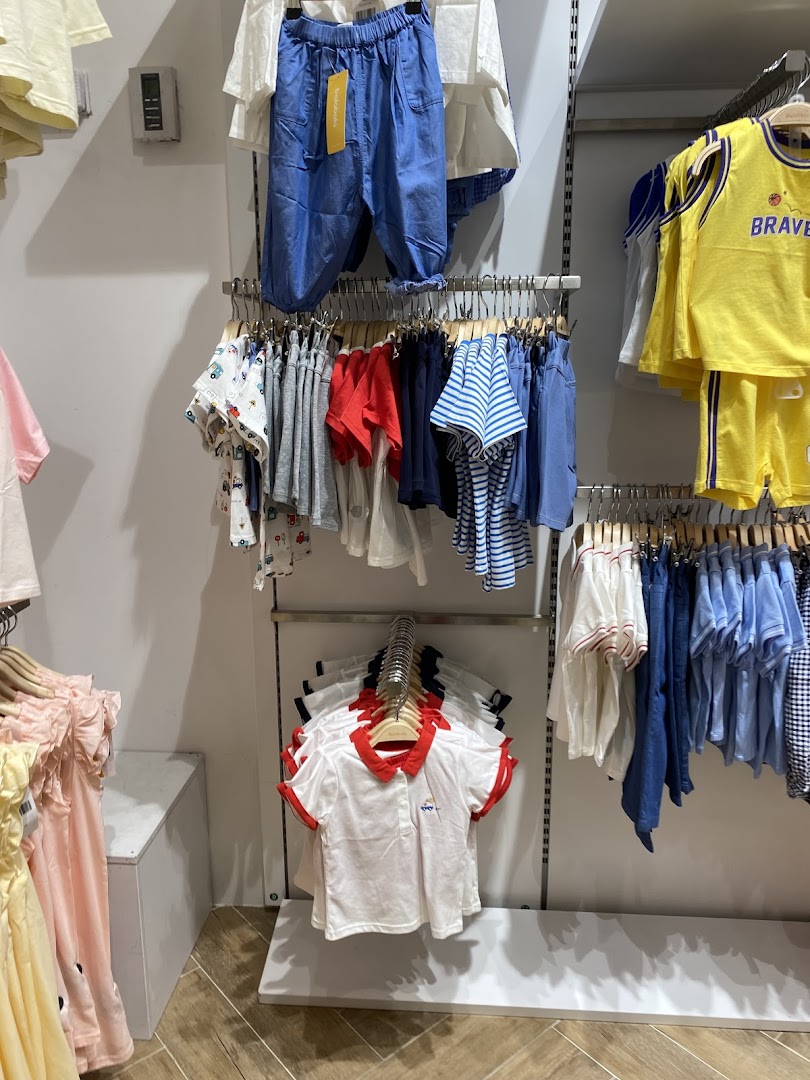 A display of colorful children's clothing, including shirts, shorts, and dresses, neatly arranged on hangers.