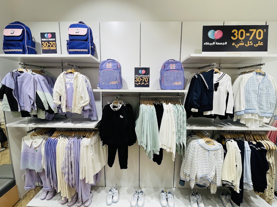 A retail shop display featuring backpacks and a variety of clothing items on racks.