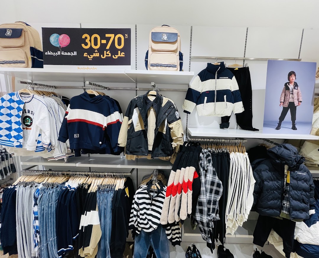 A retail shop display featuring children's clothing, including jackets, hoodies, and backpacks, with a sale banner.