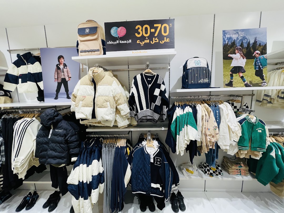 A retail display showcasing children's winter clothing, including puffer jackets, sweaters, and backpacks, with a sale sign.