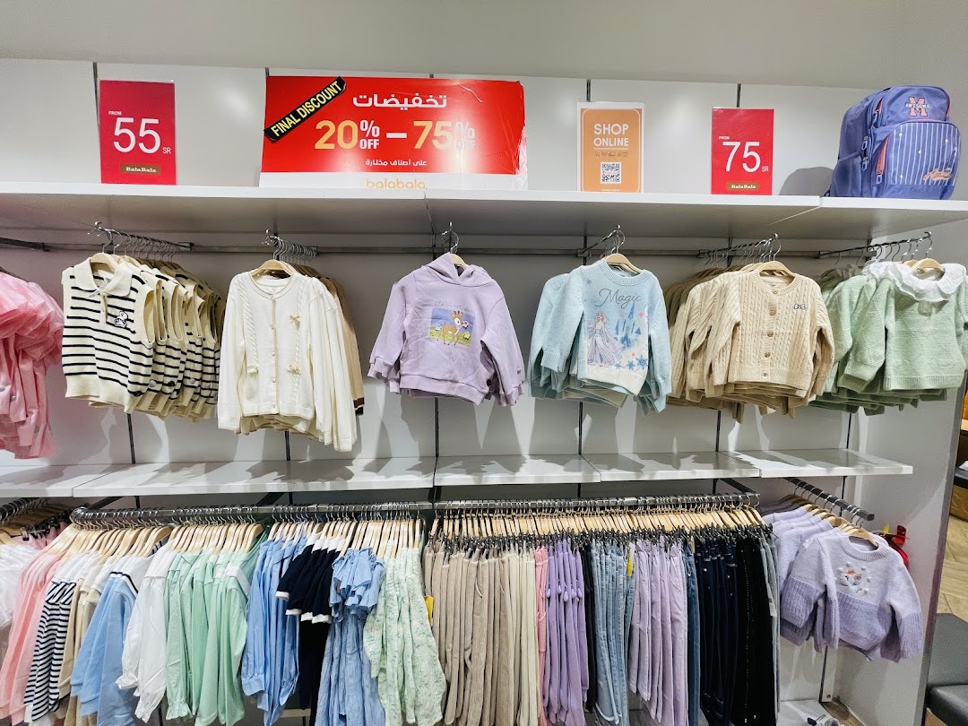 A retail shop display featuring children's clothing, including sweaters, vests, and pants, with sale signs.