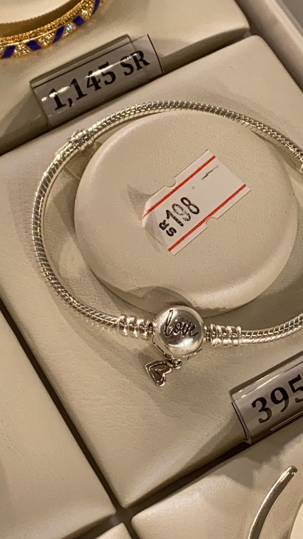 A silver Pandora bracelet with a 'love' charm and a heart pendant is displayed.