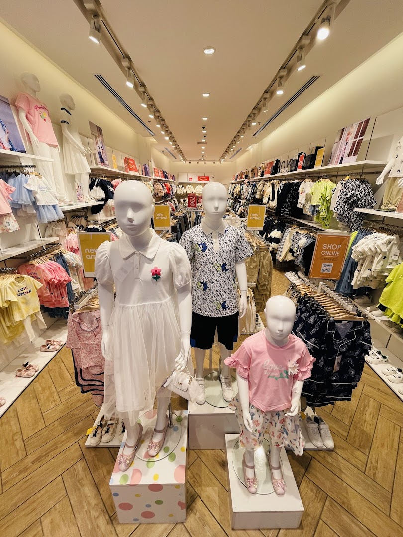 Mannequins display children's clothing and shoes in a brightly lit retail store.