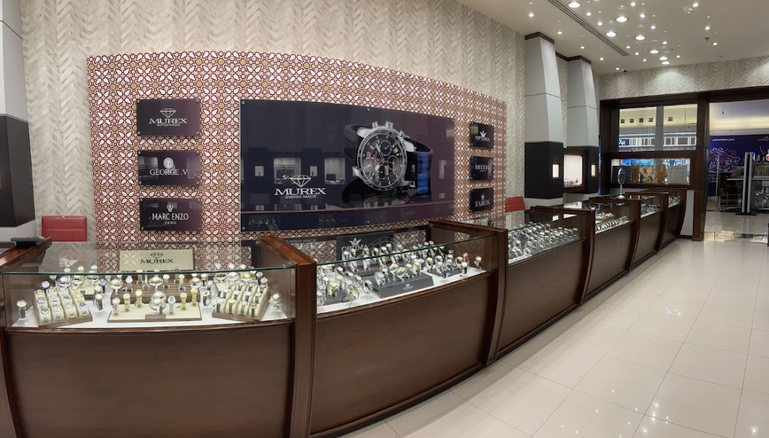 Interior view of a luxury watch store showcasing various brands and timepieces in display cases.