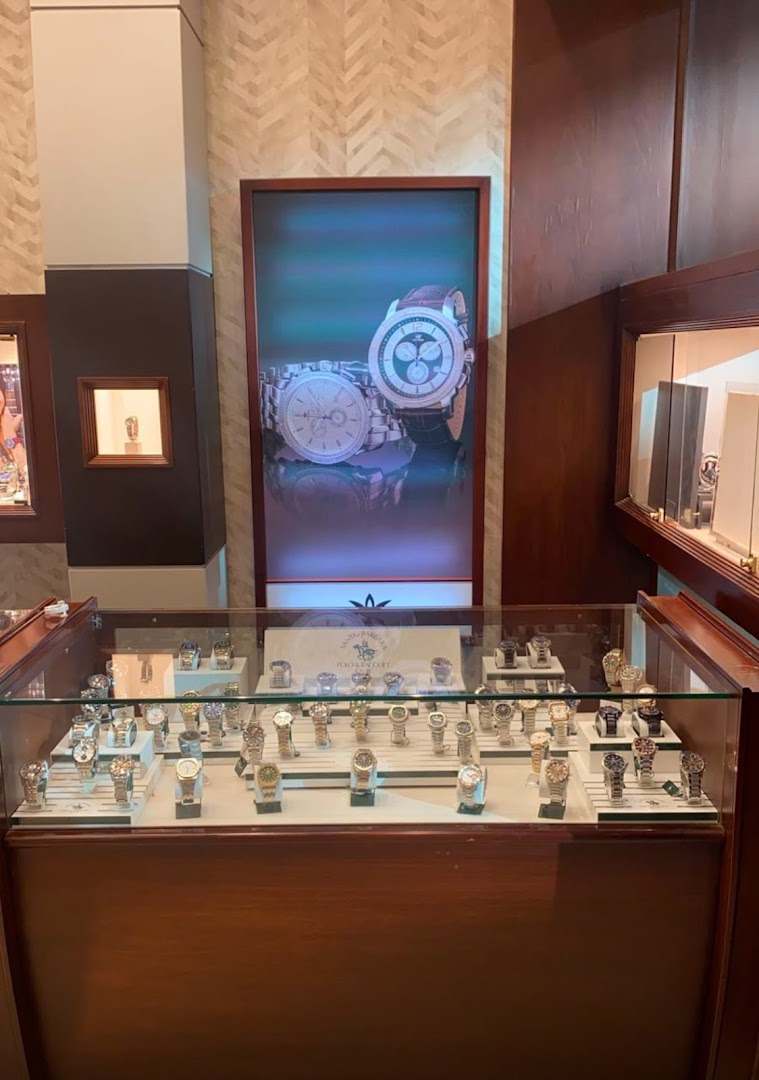 A display case filled with various watches, with a large advertisement for watches in the background.