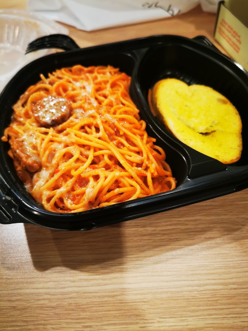 A black takeout container filled with spaghetti and a slice of garlic bread.