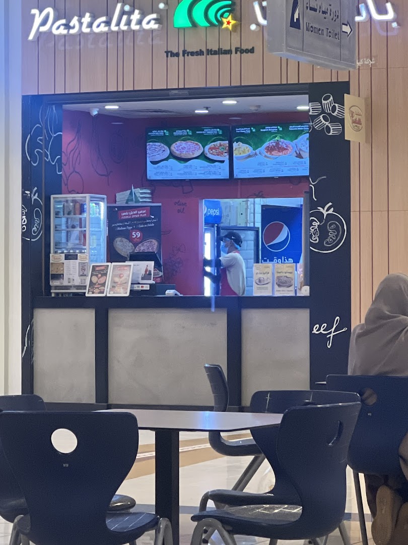 The entrance of Pastalita, an Italian food shop, with digital menus and seating.