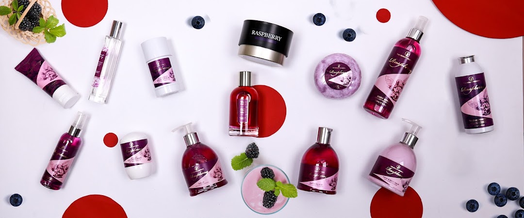 A collection of raspberry-scented beauty products arranged with fresh berries and red accents.