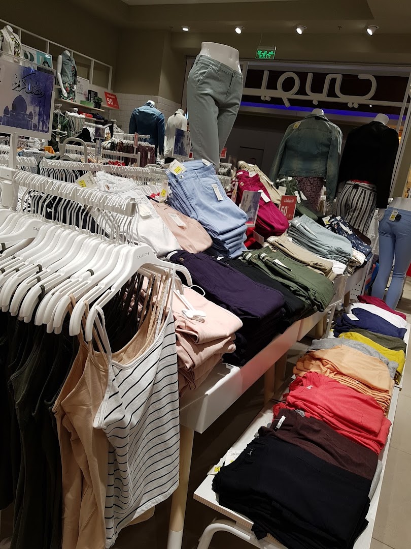 A well-organized display of colorful women's clothing, including tanks, jeans, and folded tops.