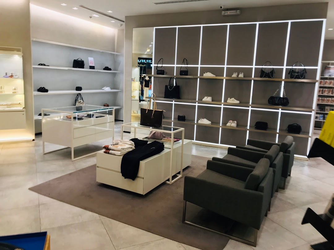 Interior of a Calvin Klein store showcasing handbags, shoes, and apparel on display shelves and tables.
