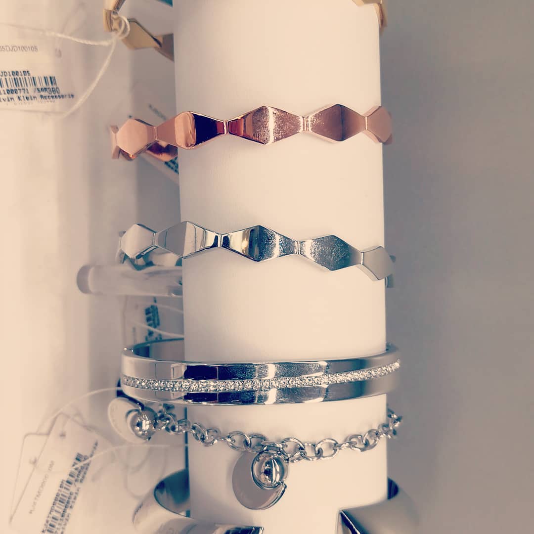 Close-up of various Calvin Klein bracelets displayed on a white stand.