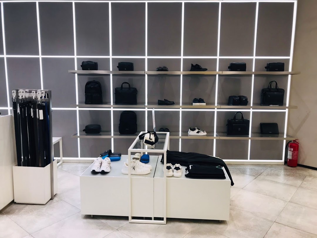 Calvin Klein store interior showcasing bags, shoes, and belts on display shelves.