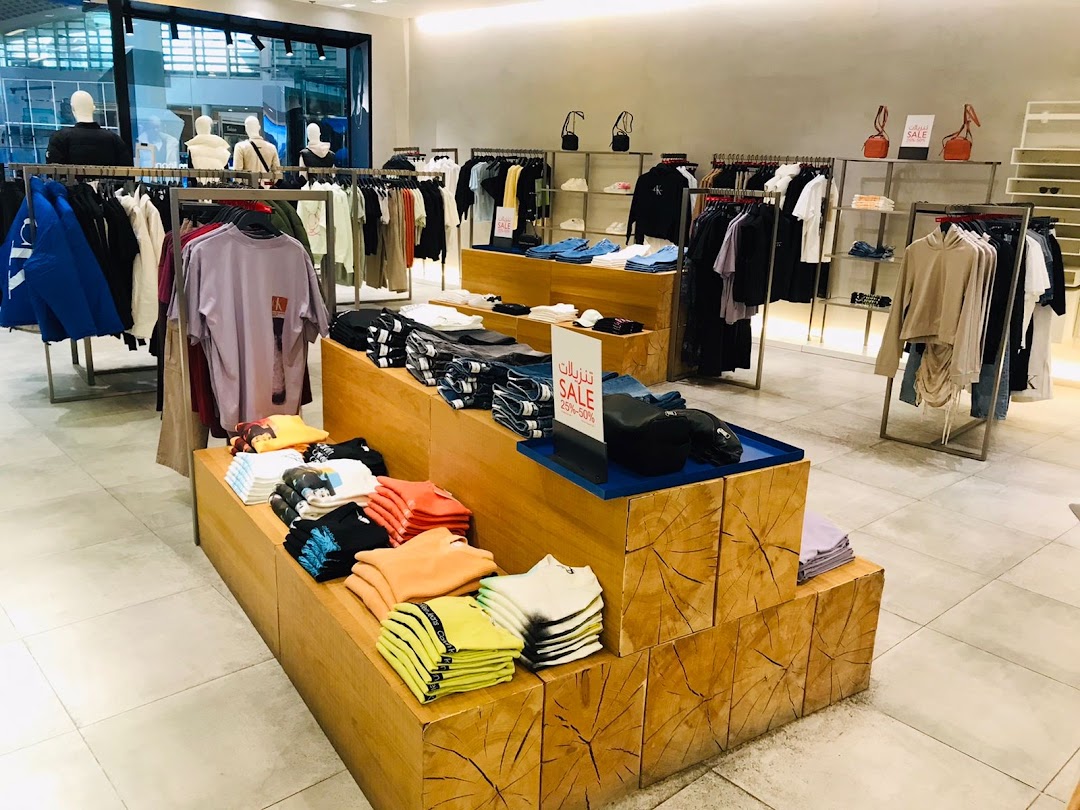 Interior view of a Calvin Klein store showcasing folded t-shirts and clothing on racks.