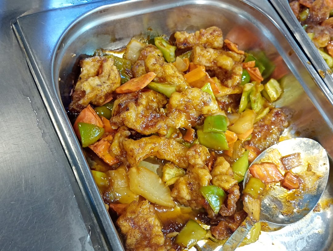 A close-up of a delicious stir-fry dish with meat, vegetables, and sauce in a metal tray.