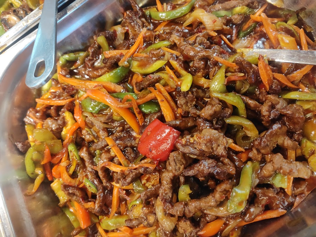 A close-up of a savory stir-fry dish with beef, peppers, and carrots in a glossy sauce.