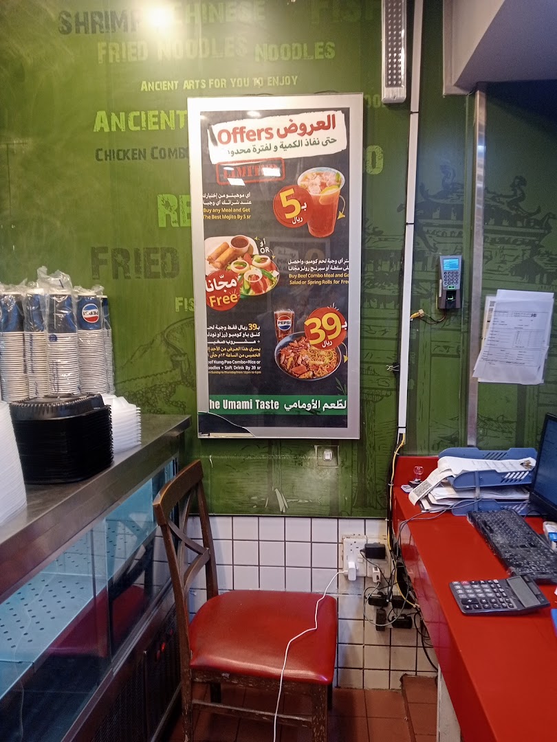 A restaurant counter with a promotional poster, chair, and computer equipment.