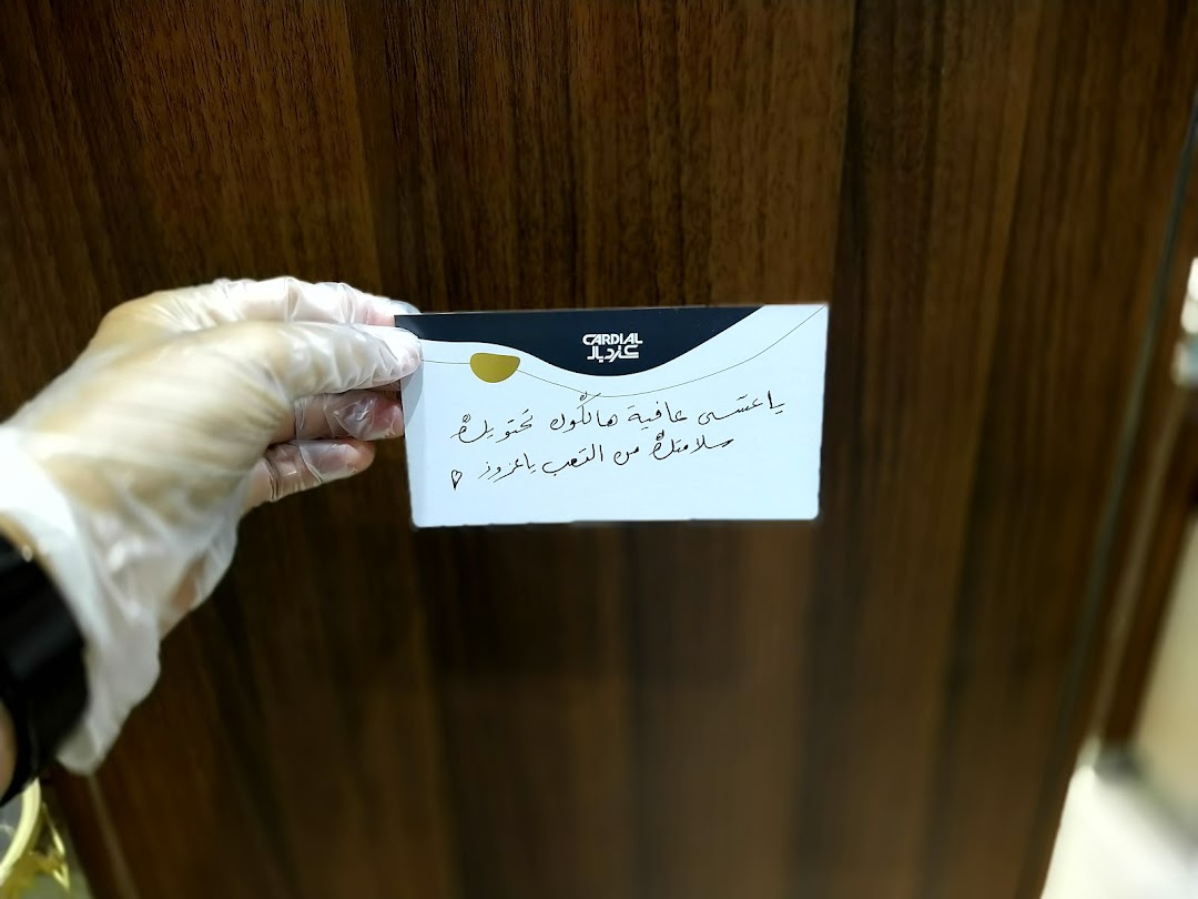 A gloved hand holds a card with Arabic text and the Cardial logo.