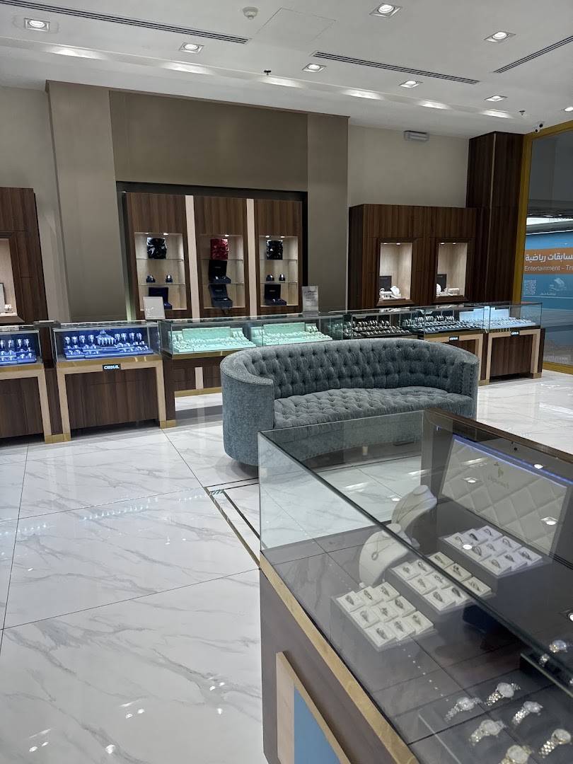 Interior of a luxurious jewelry store with display cases and a plush seating area.