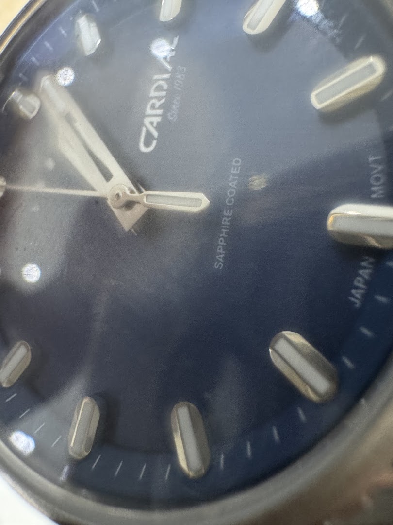 Close-up of a blue watch face with silver hands and markers, showing the Cardial logo.