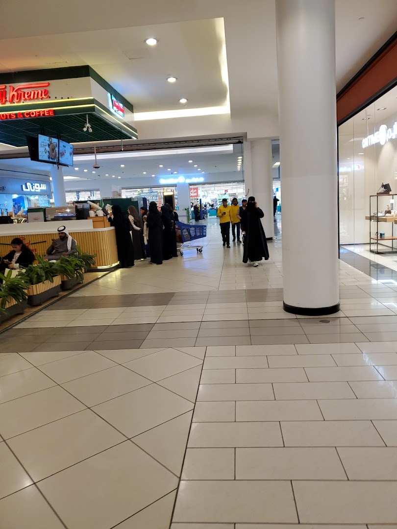 Interior view of a shopping mall with people walking and a Krispy Kreme store visible.