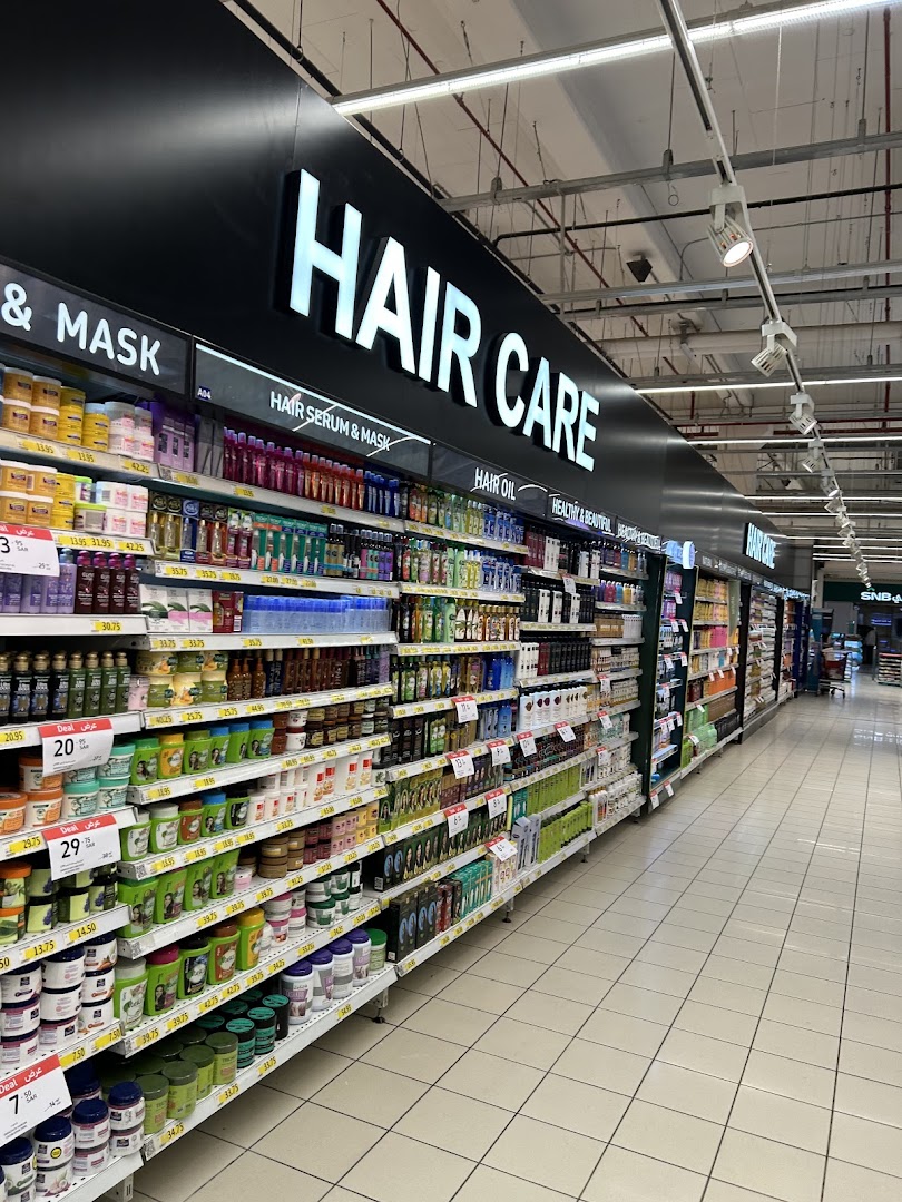 A wide aisle in a supermarket featuring shelves stocked with various hair care products.
