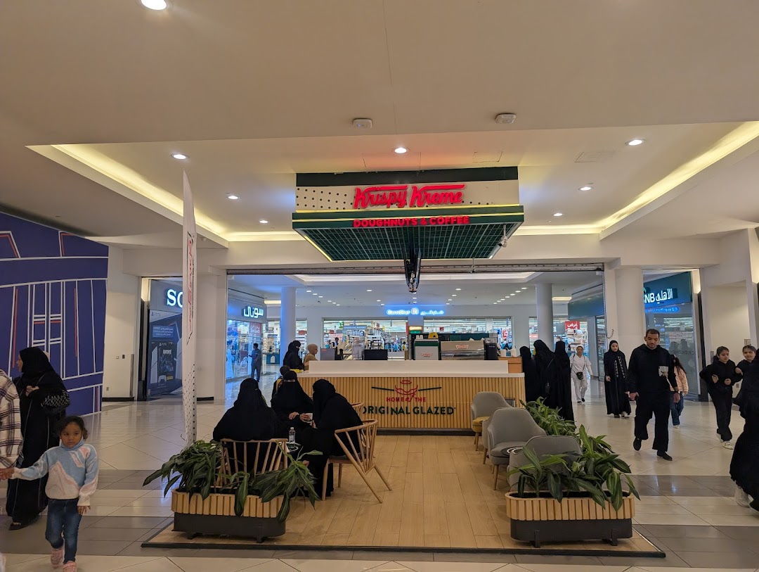 People are seated and walking around a Krispy Kreme donut and coffee shop.