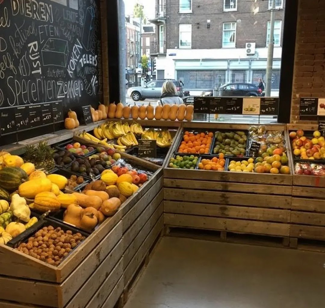 A vibrant display of fresh fruits and vegetables in wooden crates inside a grocery store.