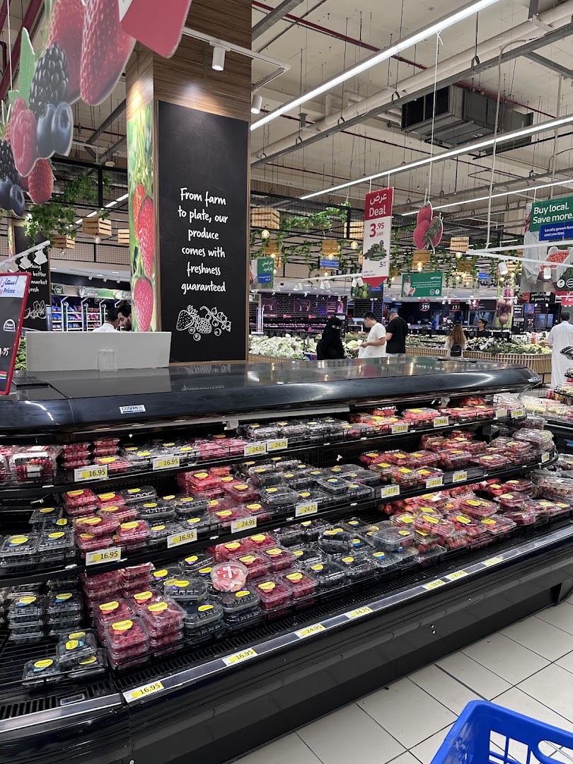 A display of fresh berries and produce in a supermarket with promotional signs.