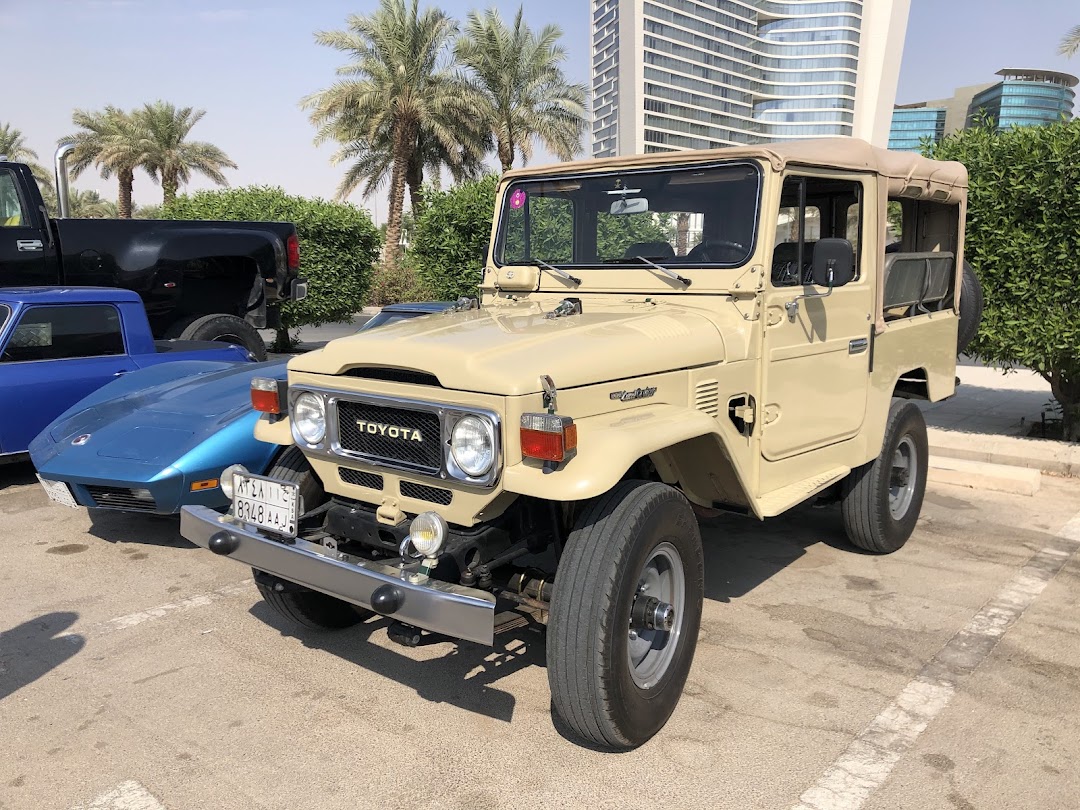 A beige Toyota Land Cruiser parked next to a blue sports car and a black pickup truck.