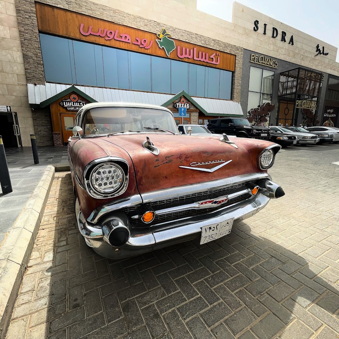 A vintage Chevrolet car parked in front of a Texas Roadhouse restaurant.
