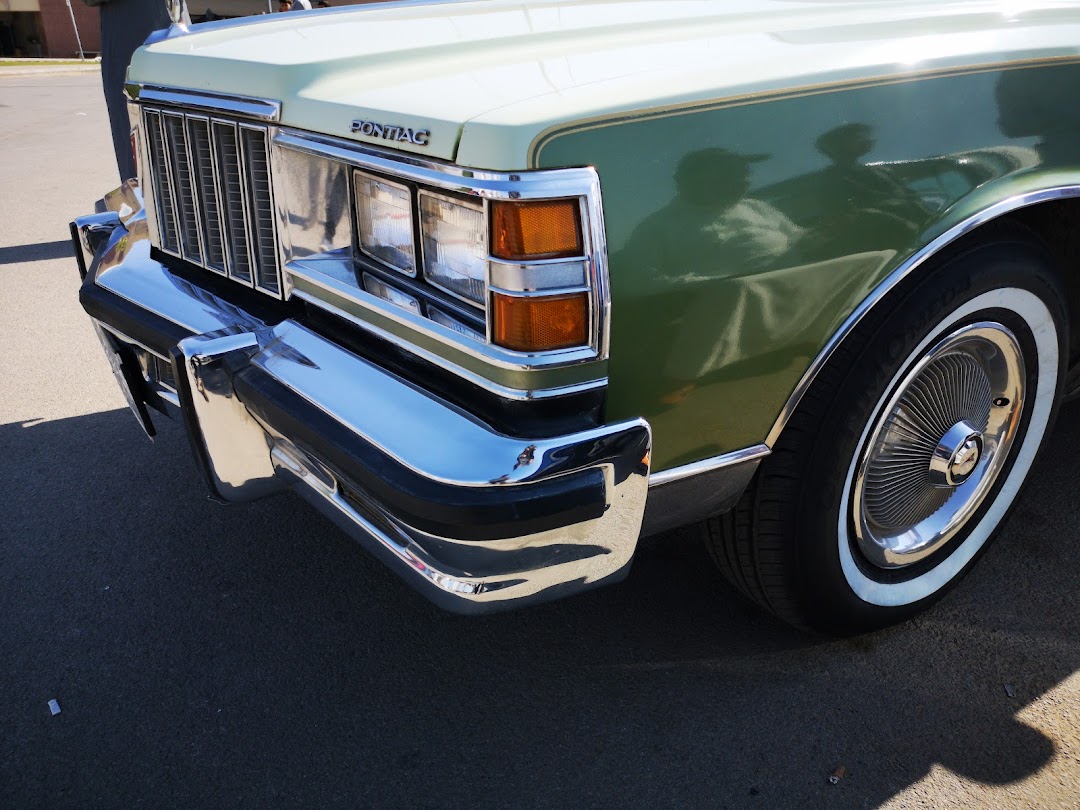 Close-up of the front fender, grille, and bumper of a vintage green Pontiac car.