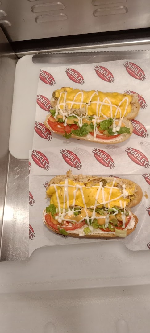 Two delicious cheesesteaks loaded with cheese, lettuce, tomatoes, and sauce on a bun.