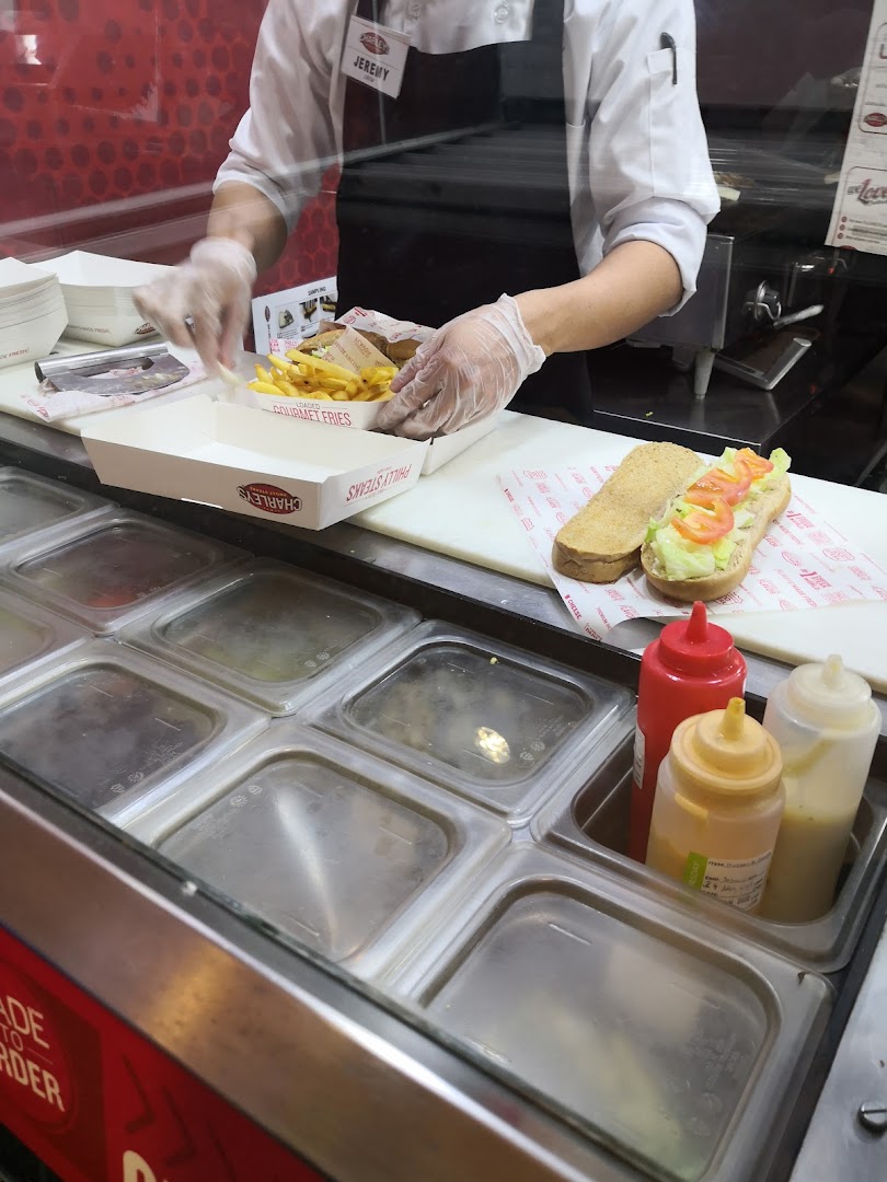 A worker is preparing a cheesesteak and fries at Charleys Cheesesteaks.