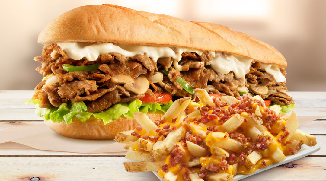 A delicious cheesesteak sandwich with a side of loaded cheese fries.