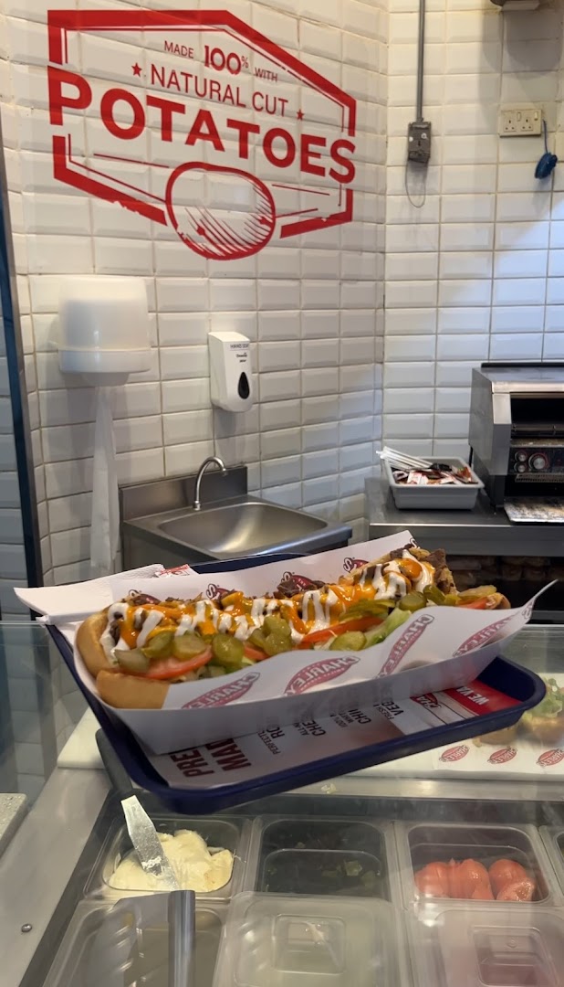 A long cheesesteak sandwich with toppings and sauces on a tray.