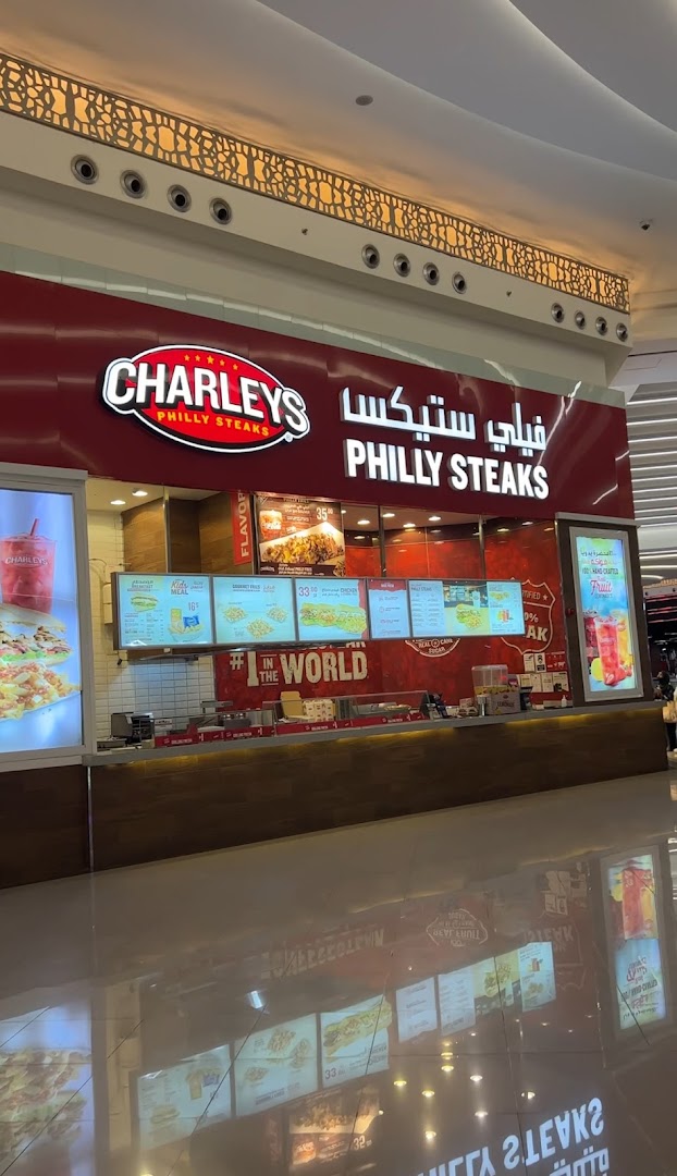 The exterior of a Charleys Cheesesteaks restaurant with illuminated menus and signage.