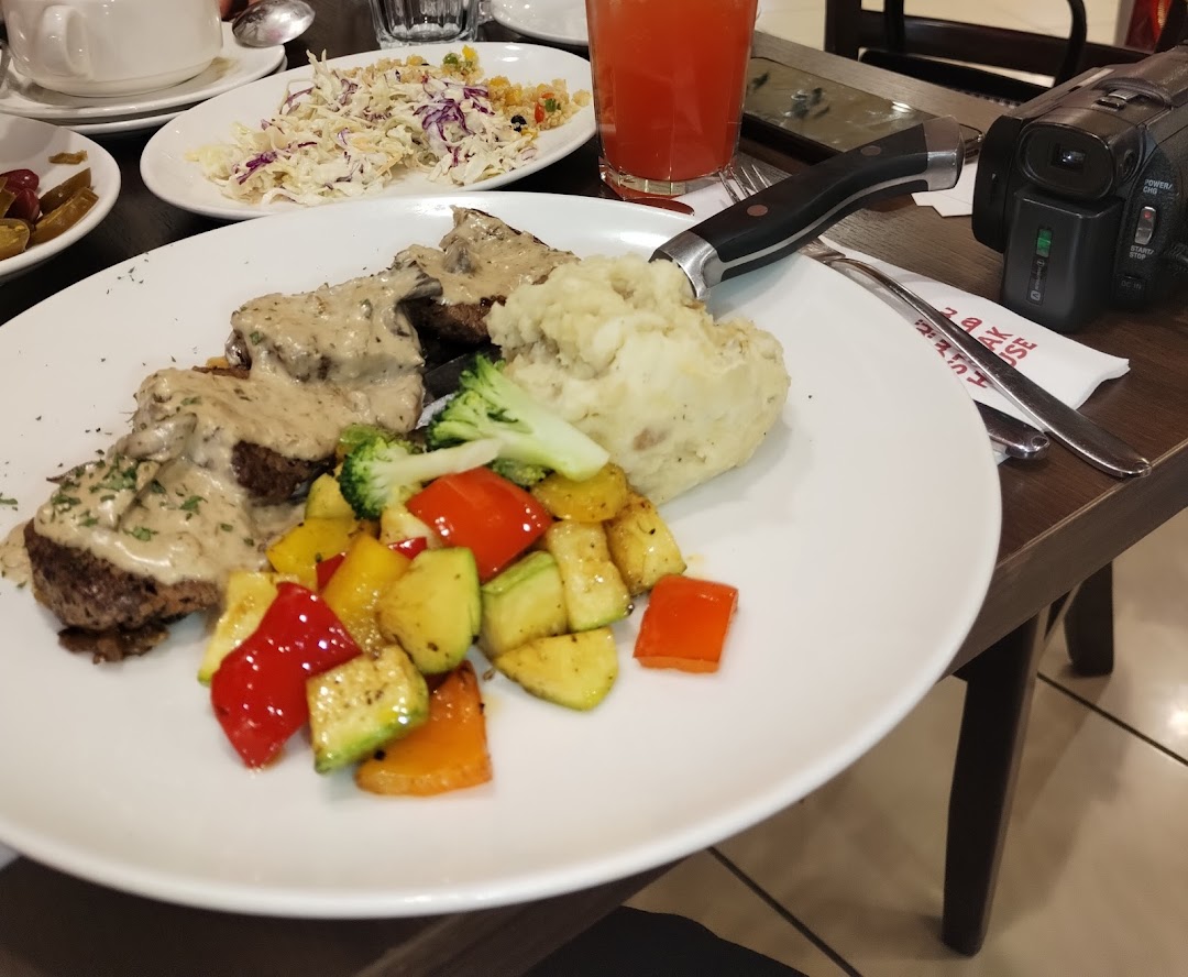 A plate of steak with mashed potatoes and mixed vegetables, served with a side of coleslaw.