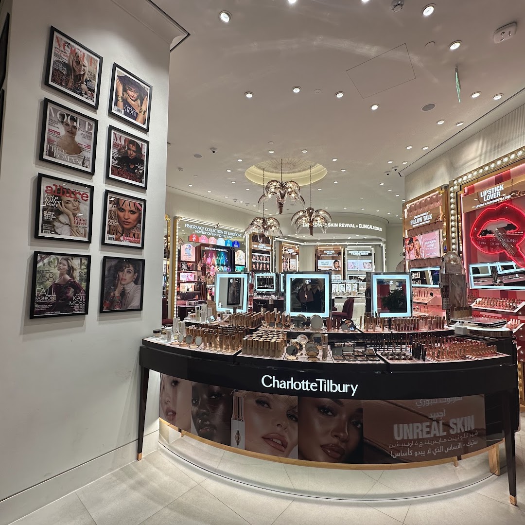 Interior of a Charlotte Tilbury beauty store with makeup displays and fashion magazine covers on the wall.