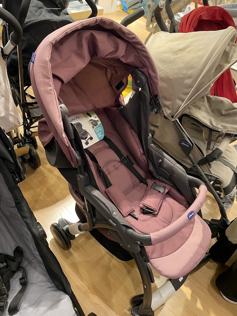 A close-up view of a pink Chicco stroller with other strollers in the background.