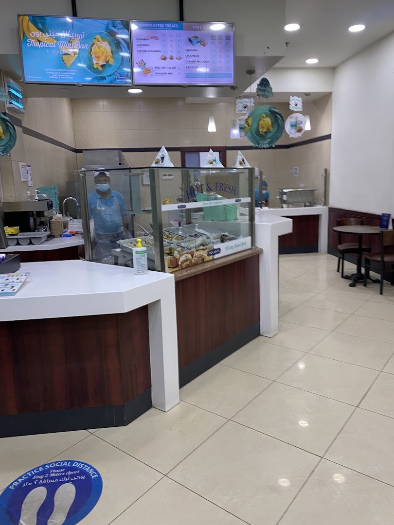 Interior view of a Cinnabon shop with a display case and menu boards.