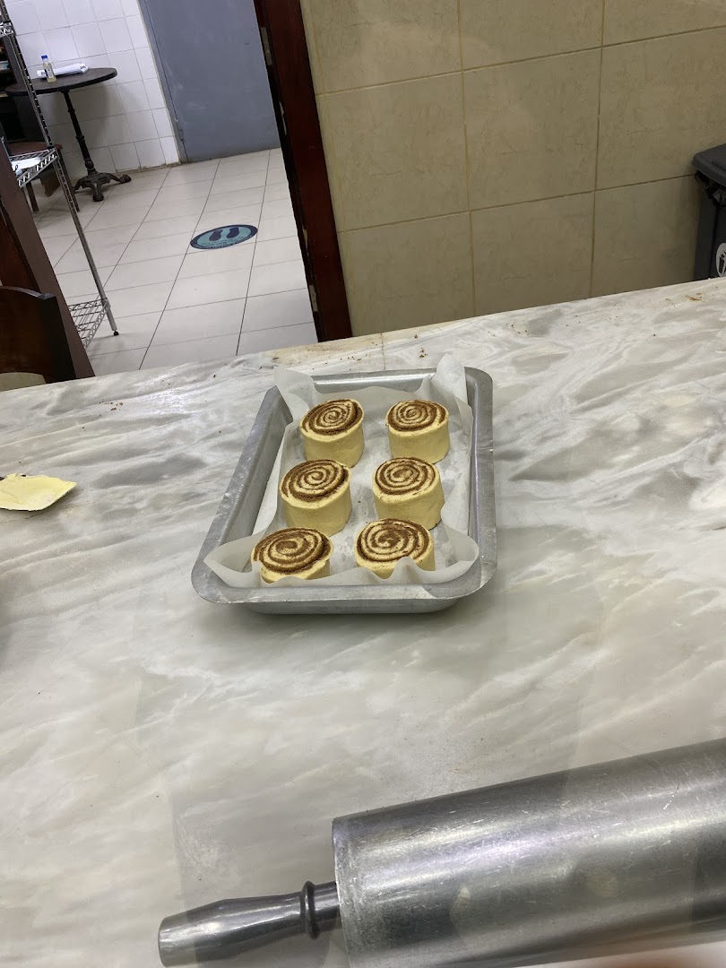 A tray of freshly prepared cinnamon rolls ready for baking, with a rolling pin in the foreground.