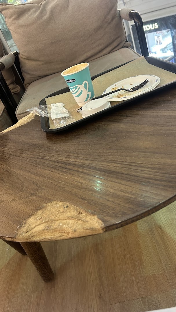 A Cinnabon cup and used plate on a tray next to a chair.