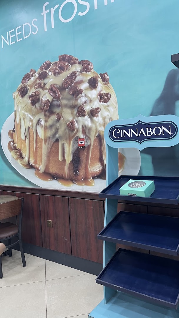 A Cinnabon display featuring a large cinnamon roll image and empty shelves.