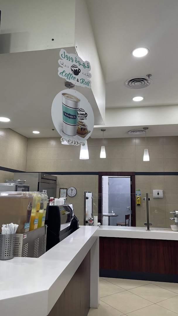 Interior view of a Cinnabon shop with a counter, drinks, and signage.