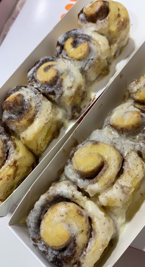 Close-up of freshly baked Cinnabon cinnamon rolls with cream cheese frosting.