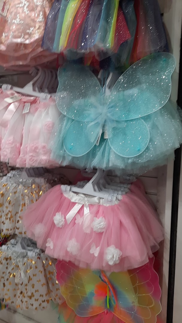 A display of colorful tutus and fairy wings for children.