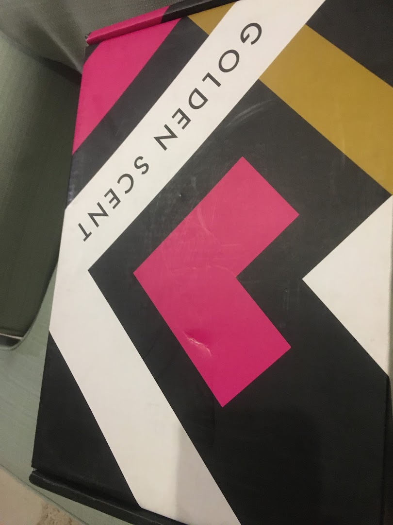 A box with the text "GOLDEN SCENT" in black lettering on a geometric pattern.