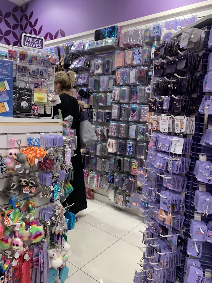 A woman browses a Claire's store filled with phone cases and accessories.