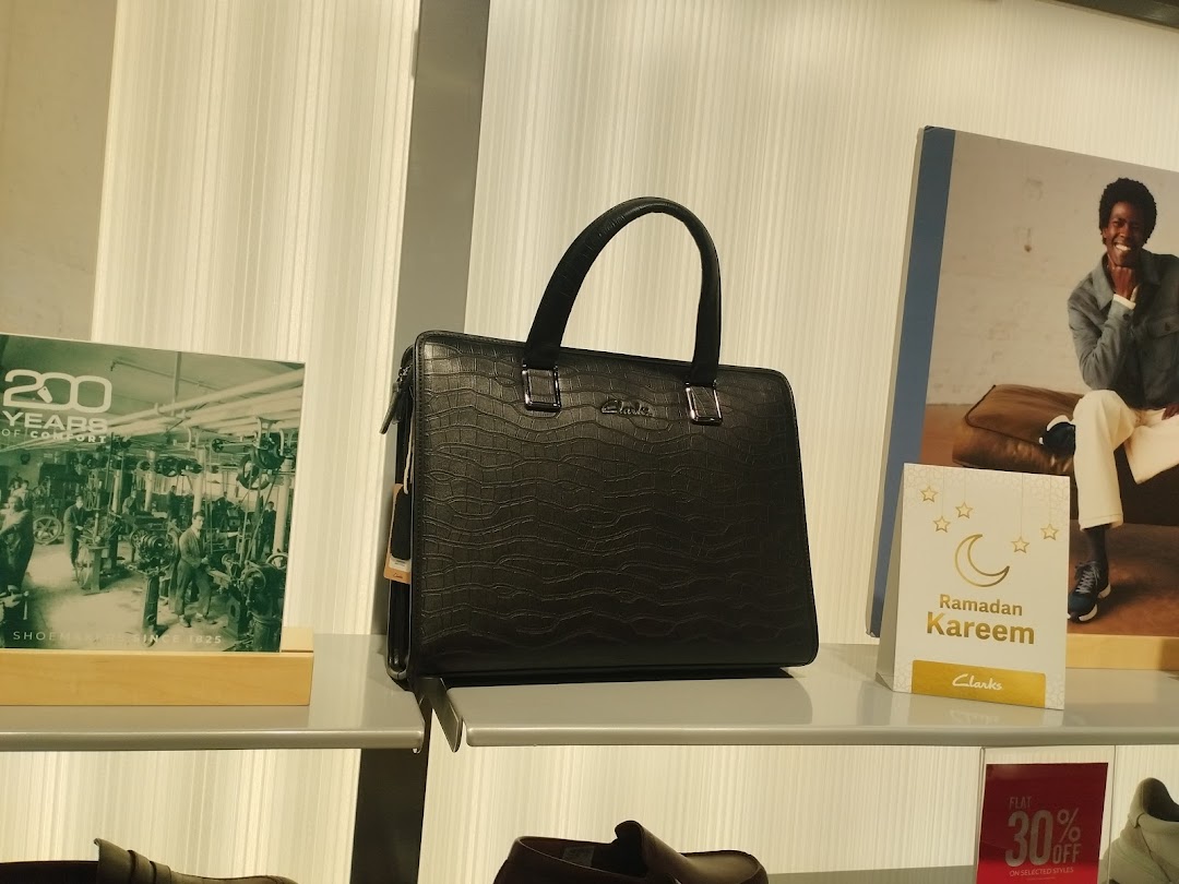 A black embossed handbag is displayed on a shelf with promotional materials.